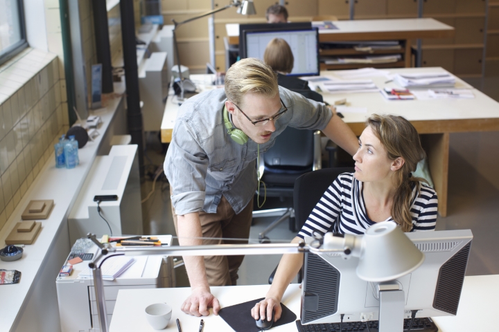 man and women talking in a office with computers