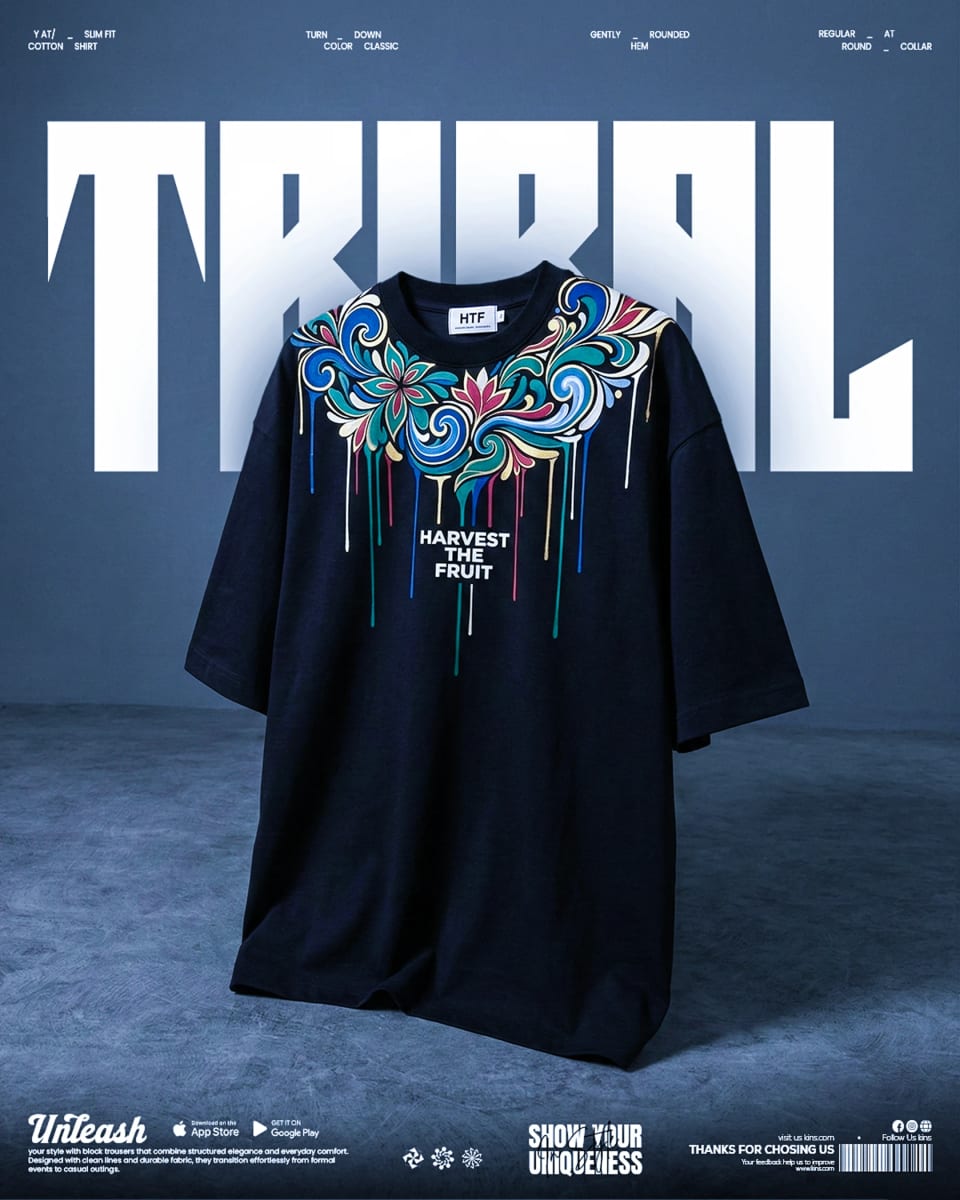 A striking dark blue t-shirt with a colorful, intricate floral paint-drip graphic reading "HARVEST THE FRUIT," floating in front of bold white "TRIBAL" typography.