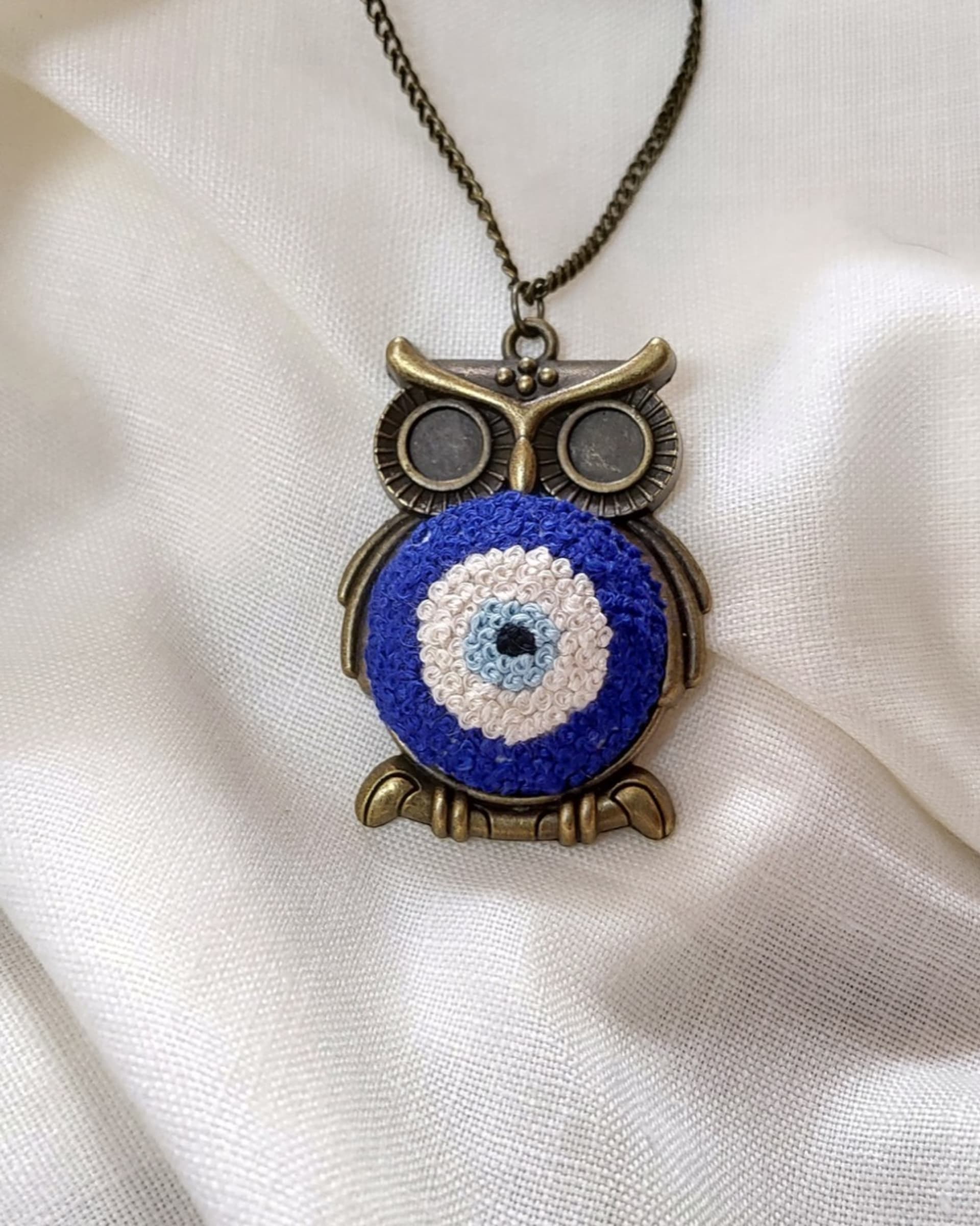 Owl evil-eye embroidered pendant on white linen