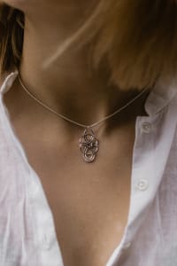 Small silver orbit-shaped pendant on neck