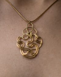 Close-up of intricate wire-formed gold pendant on chest