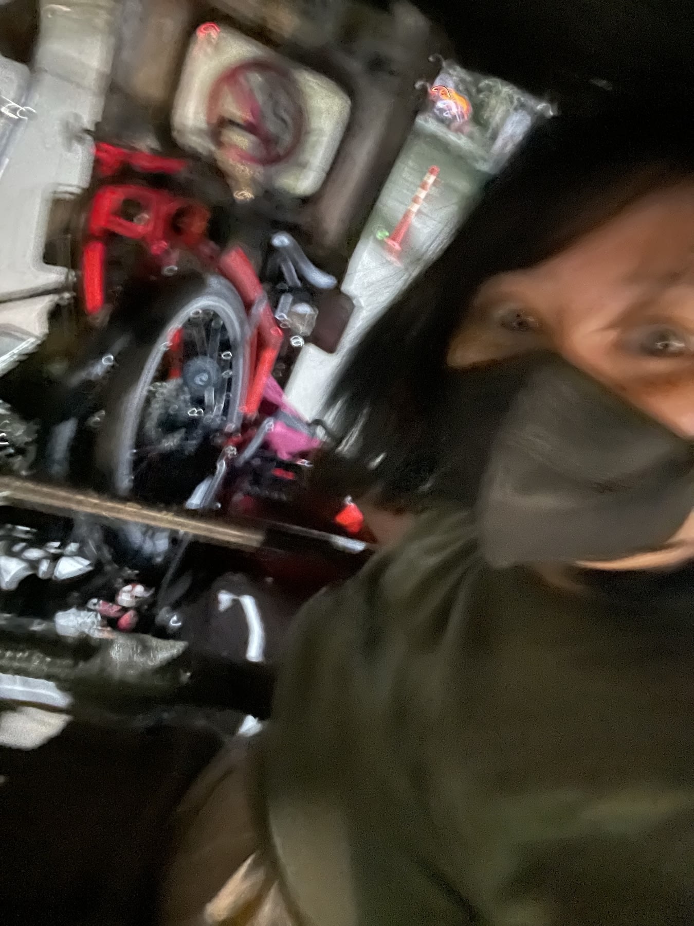 A selfie of Chi wearing a mask and at the back of a tricycle, while holding onto her folded folding bike which was neatly tucked in the inner seat of the tricycle. It's a bit blurry because it's dark and the only source of light for the photo is the occasional streetlight.