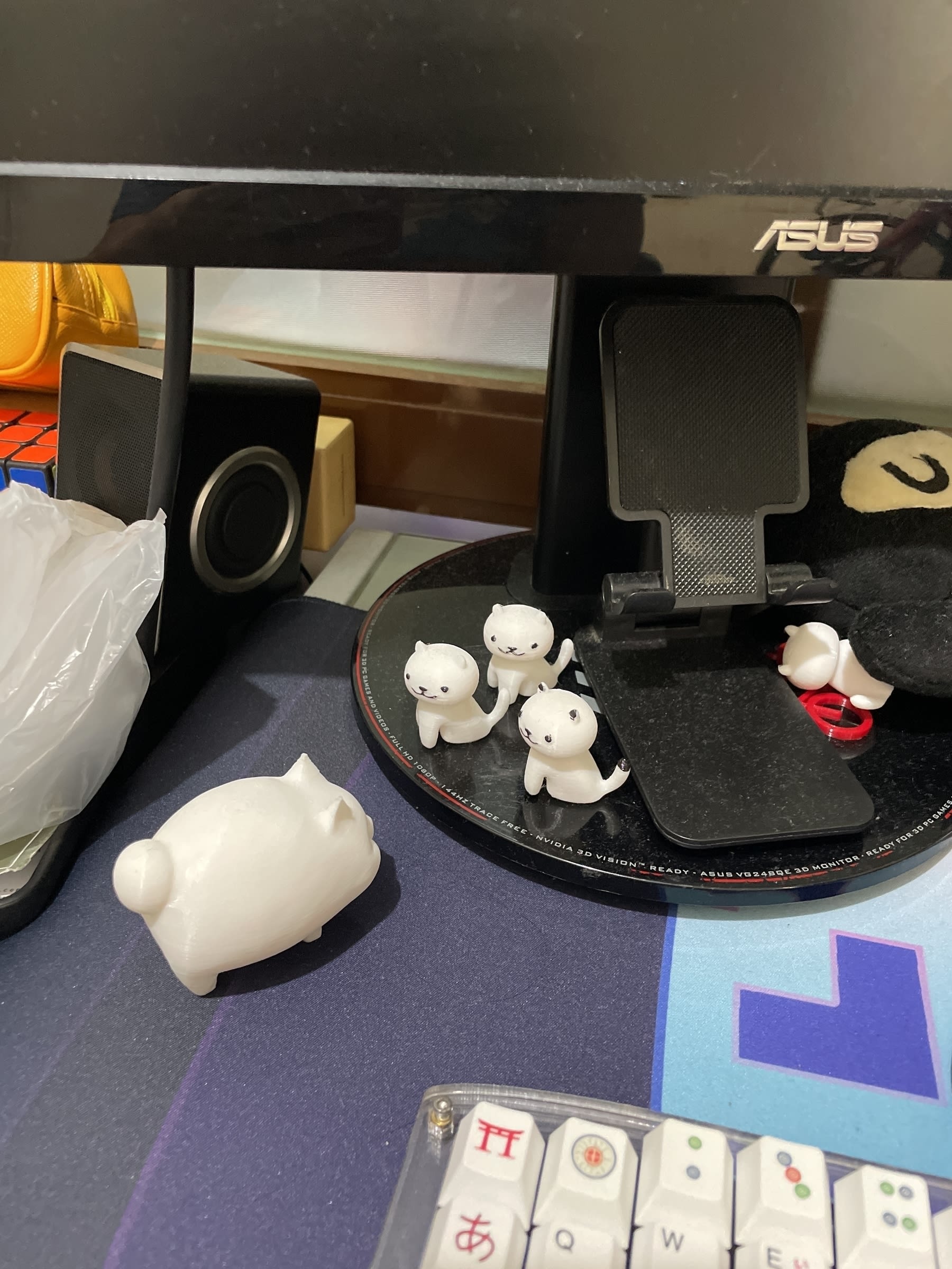 3 3d-printed small cats are found facing a 3d-printed fat cat on Chi's desk. The small cats are on the monitor stand.
