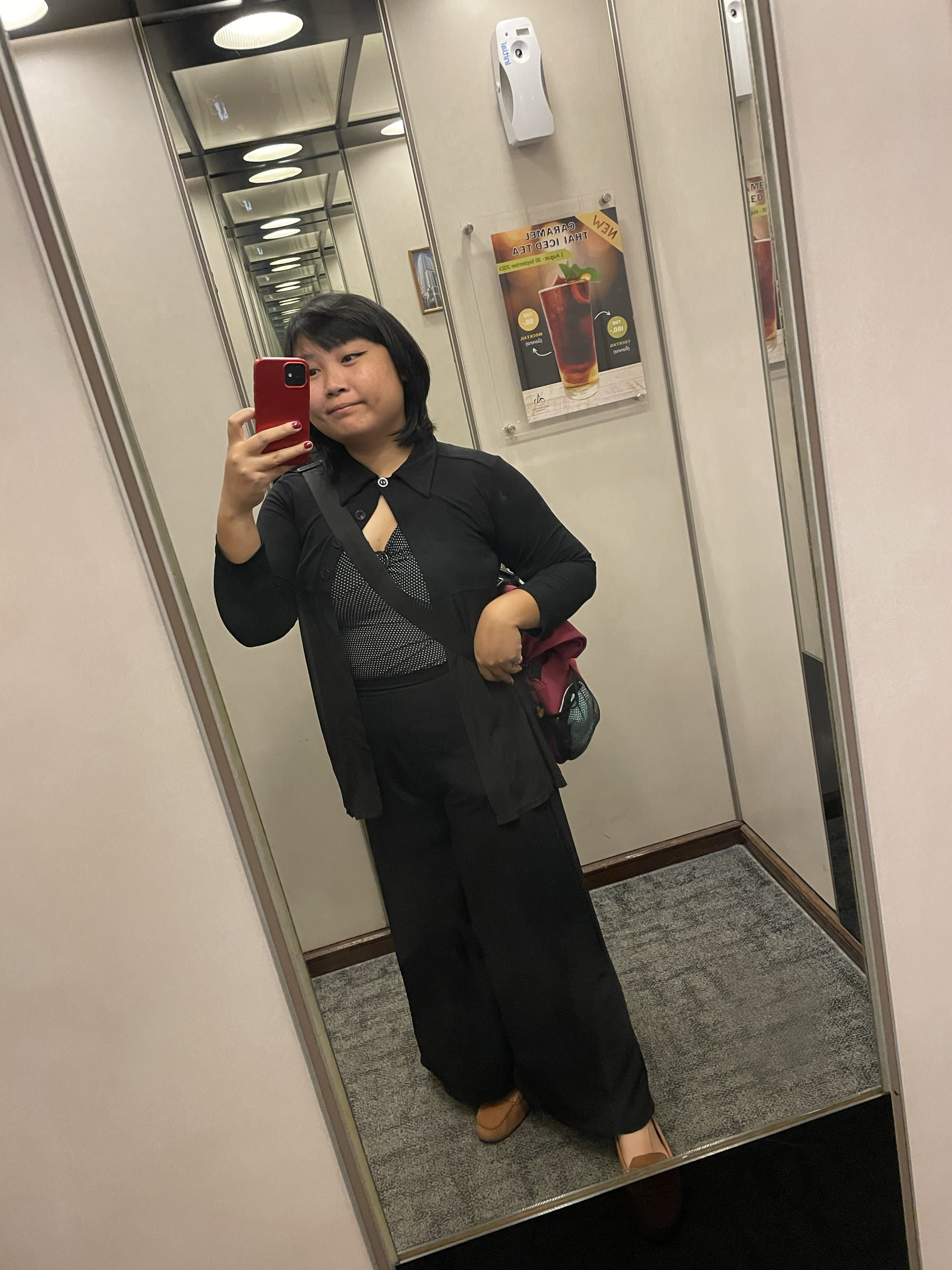 Chi's outfit for the day shown in a mirror selfie: white polka-dot on black v-neck fitted top with a sheer black long sleeved collared coverup, and long black flared pants.