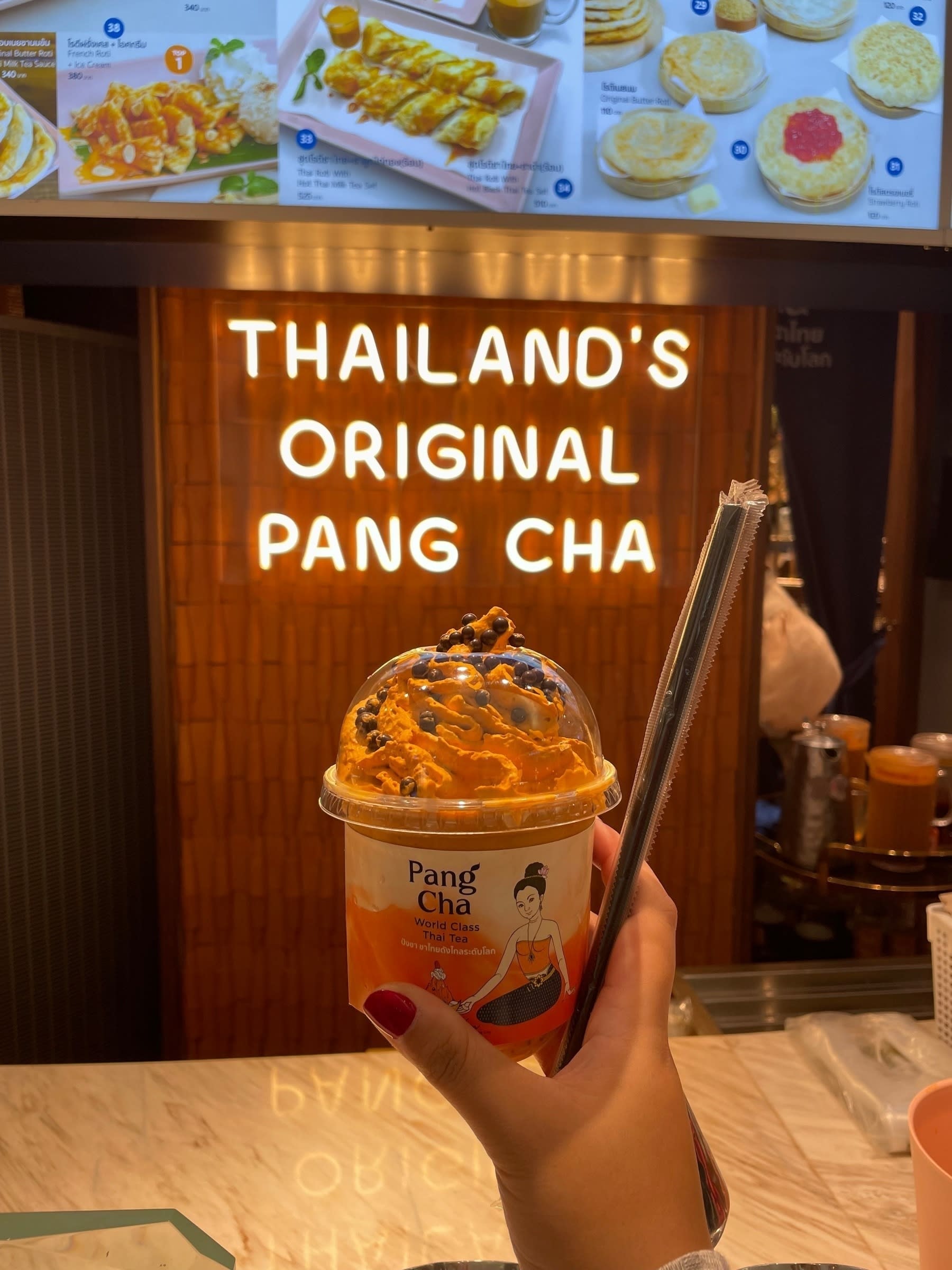 Chi’s order of Thai milk tea with choco caviar from Pang Cha, which is raised under the neon orange sign that reads: “Thailand’s original Pang Cha”.