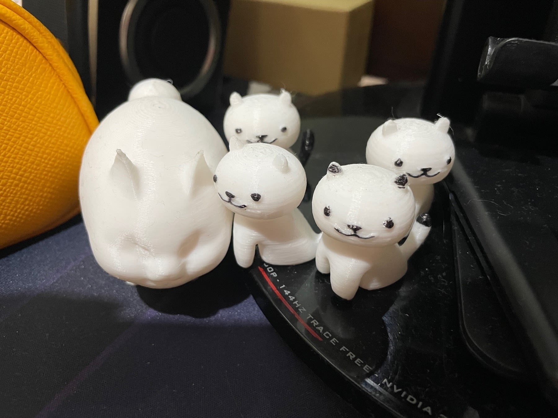 Chi’s 3d-printed cats, given to her by her boyfriend. She has one big fat cat, which is based on the fat cat in FFXIV, and 4 smaller Neko Atsume style cats that have their eyes, nose, mouths, and some patterns colored in with a black marker.