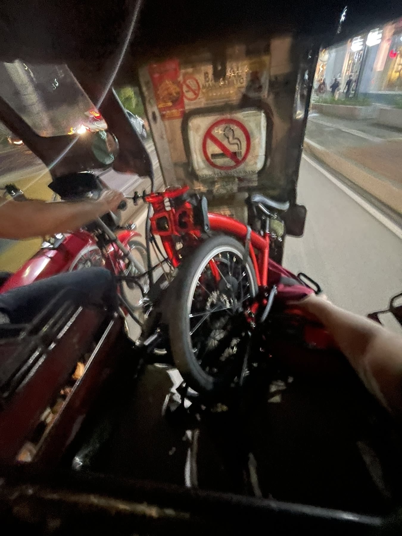 Chi's folding bike in the middle of a tricycle's cabin, folded neatly to fit within the seat. Chi's bag, which usually is attached to the front of the bike, is found on the right side of the bike, near the tricycle's entrance, to help keep it in place as the trip goes on.