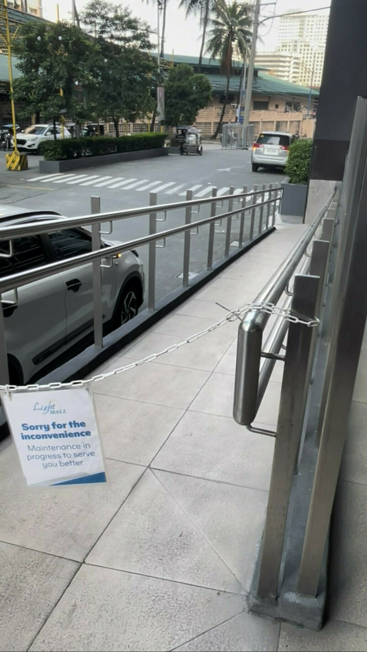 A ramp meant to make the entrance more accessible to PWDs, but is cordoned off with a sign on it that reads, "Sorry for the inconvenience / Maintenance in progress to serve you better" by SM Light Mall.