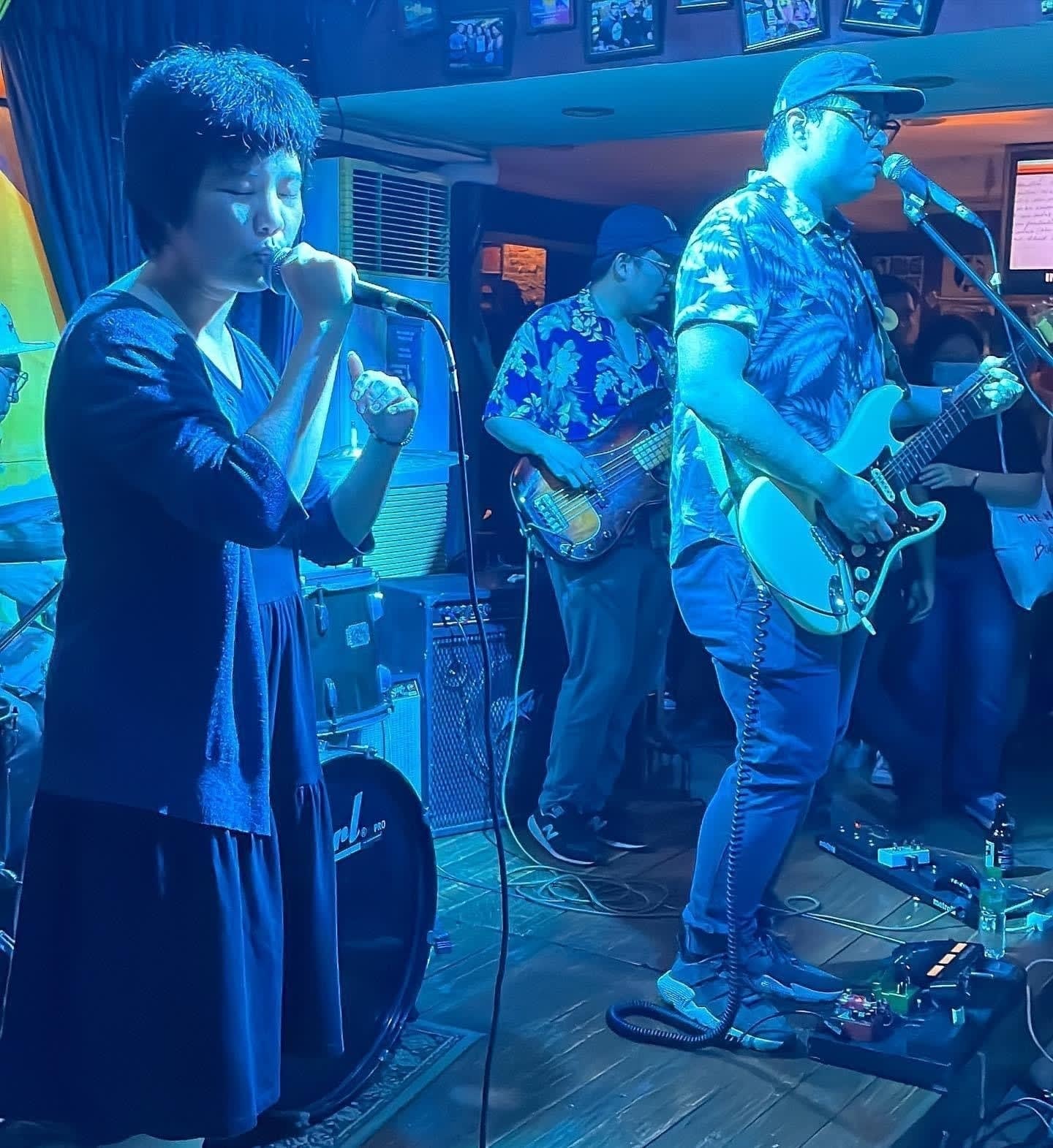 Banna Harbera performing at the 2022 Fête de la Musique Philippines. Both the main vocalist and lead guitar and vocalist are lit in a cool blue hue. Both of them are focused on singing the song, as shown in their expressions.