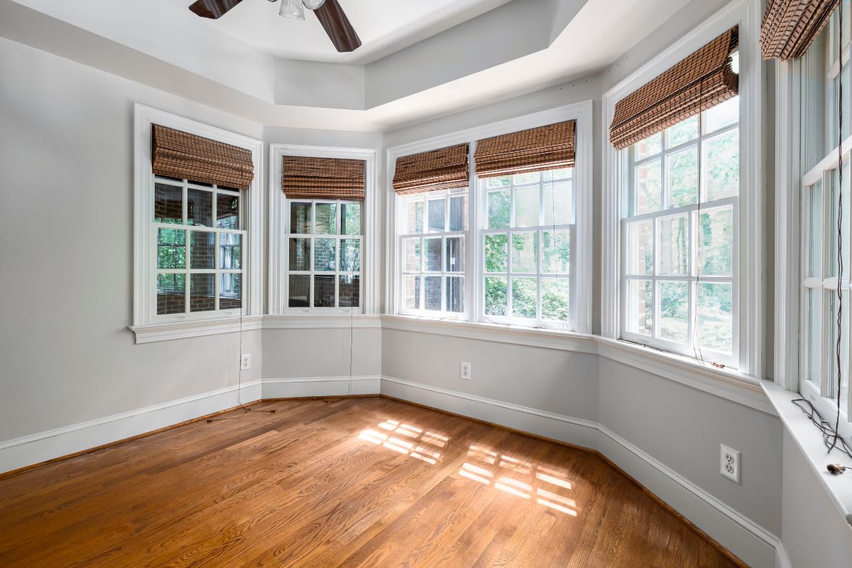 An empty room with hardwood floors and windows.