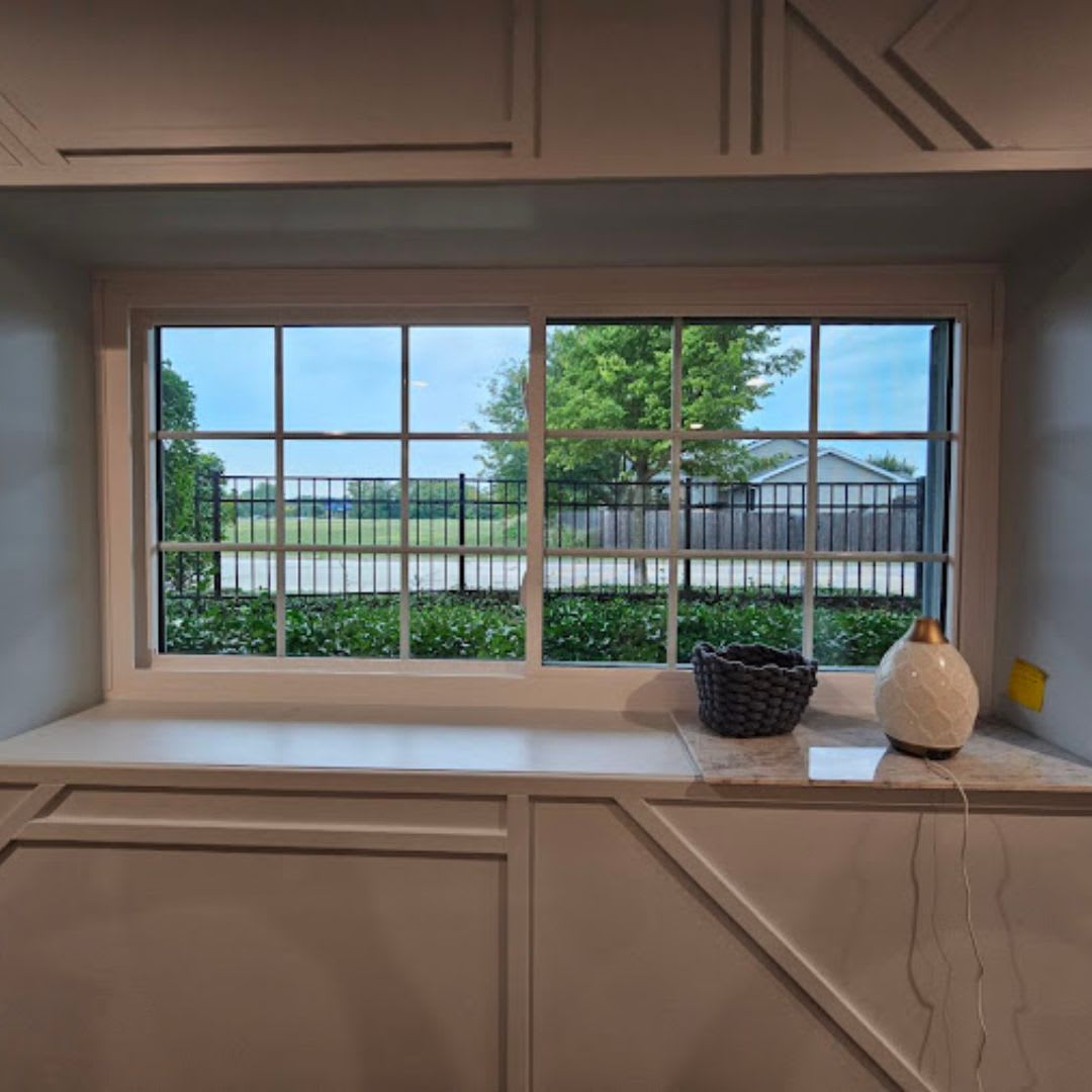 A window in a kitchen with a view of a field.