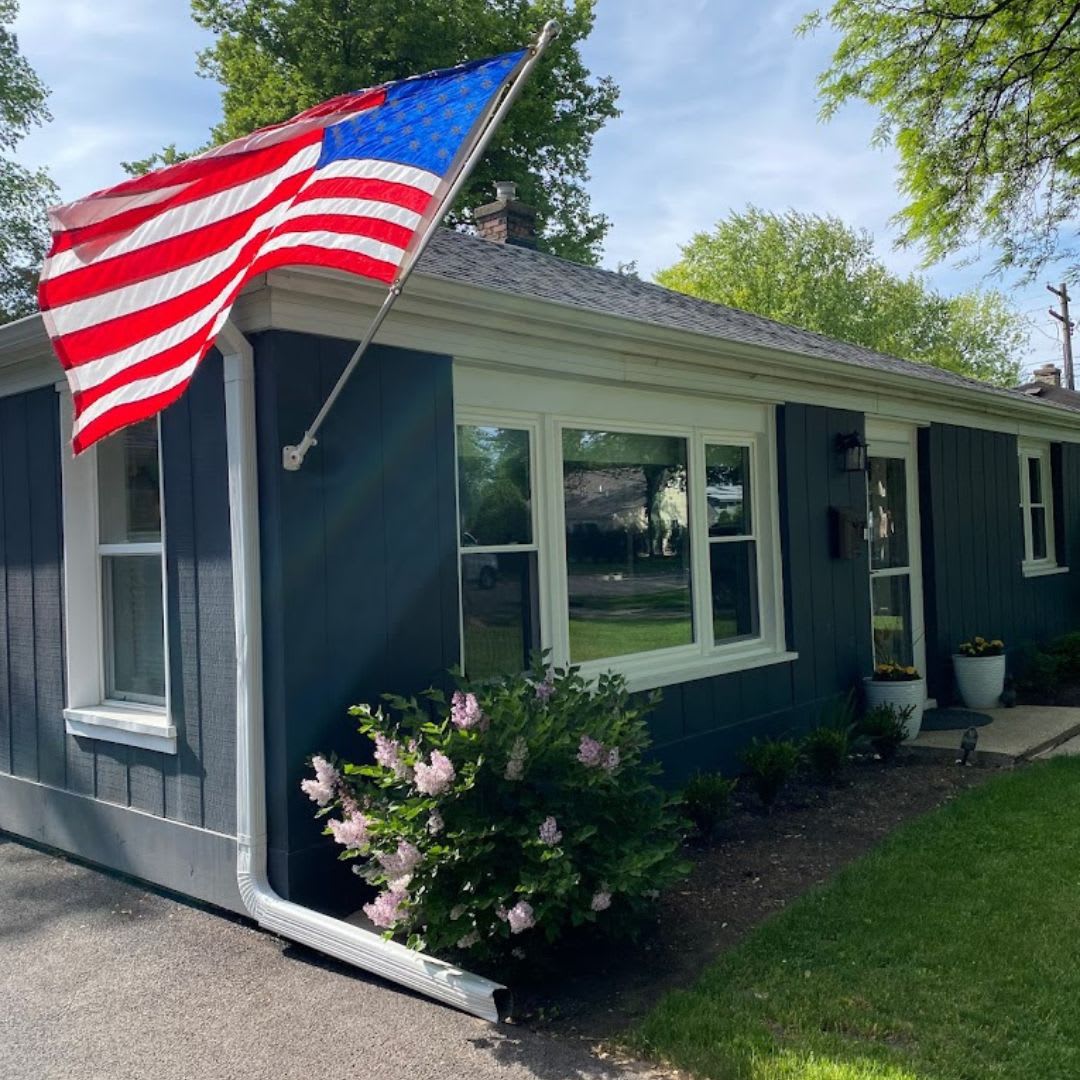 A blue house with an american flag on the front porch.