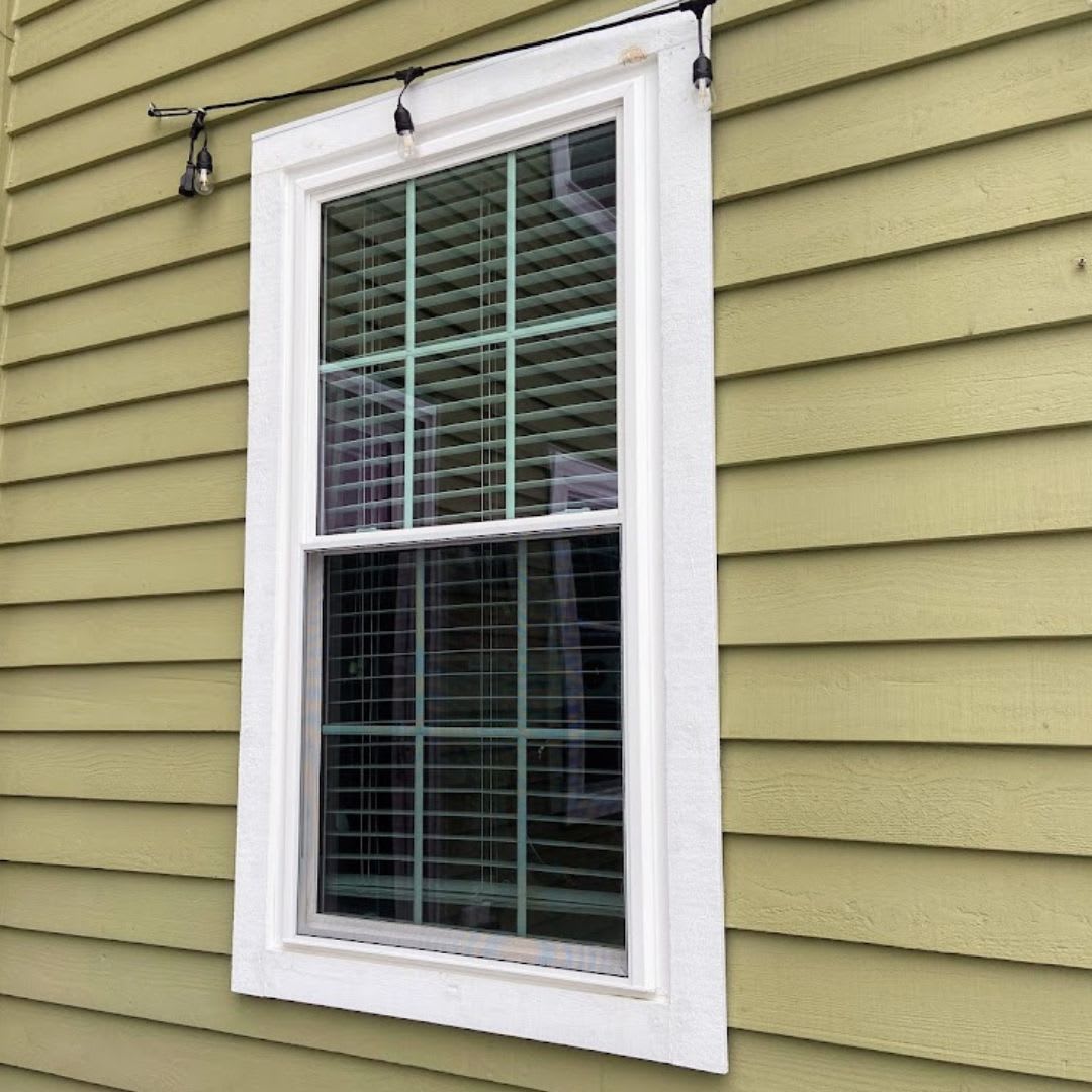 A window on a house with green siding.