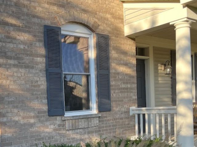 A brick house with a front porch and shutters.