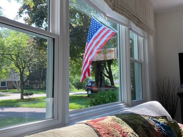 An american flag hangs from a window in a living room.