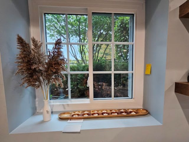 A tray of donuts sits on a window sill.