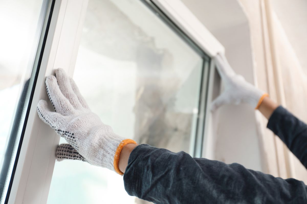 Person wearing gloves installing a window pane.