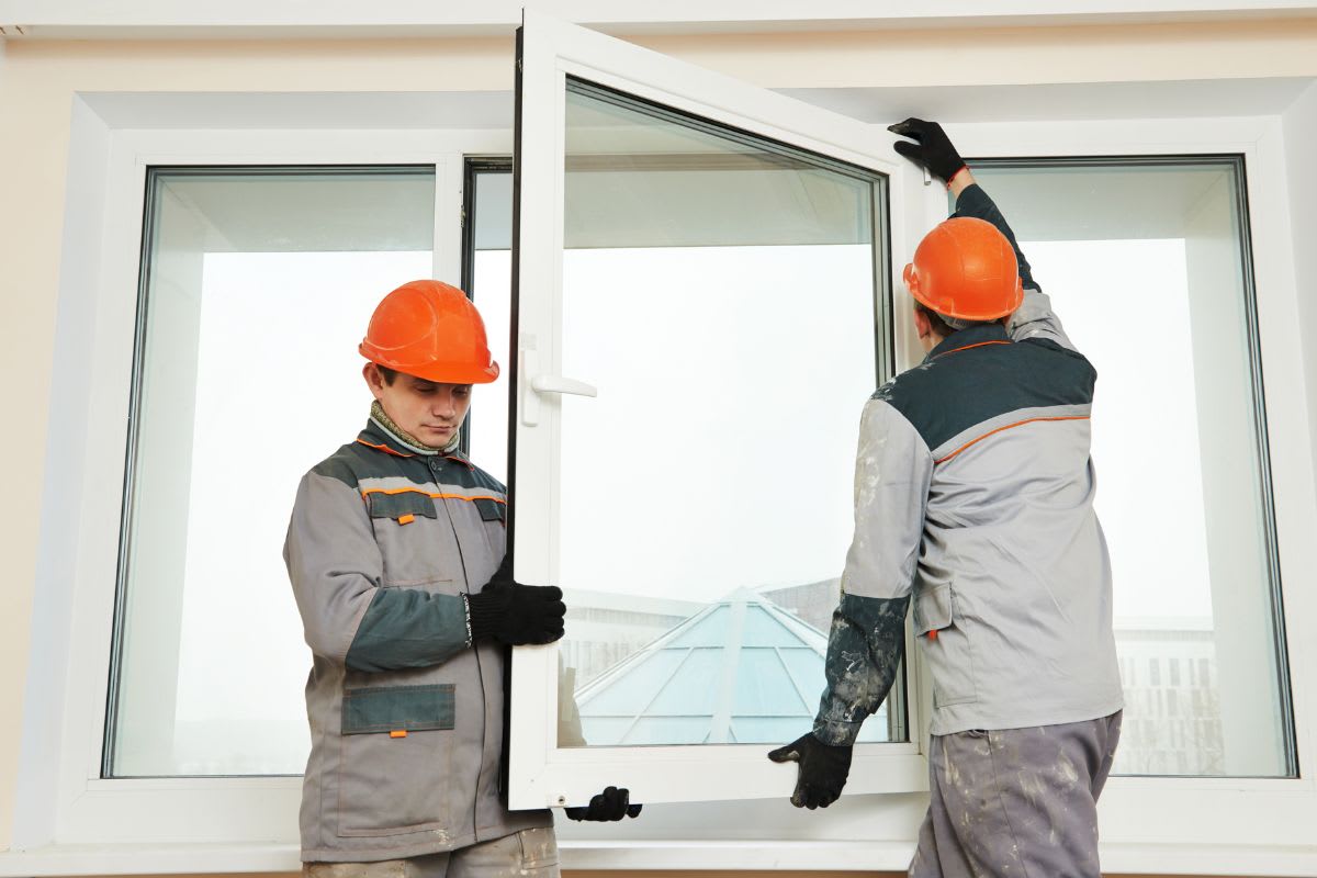 Two workers installing a window in a building.