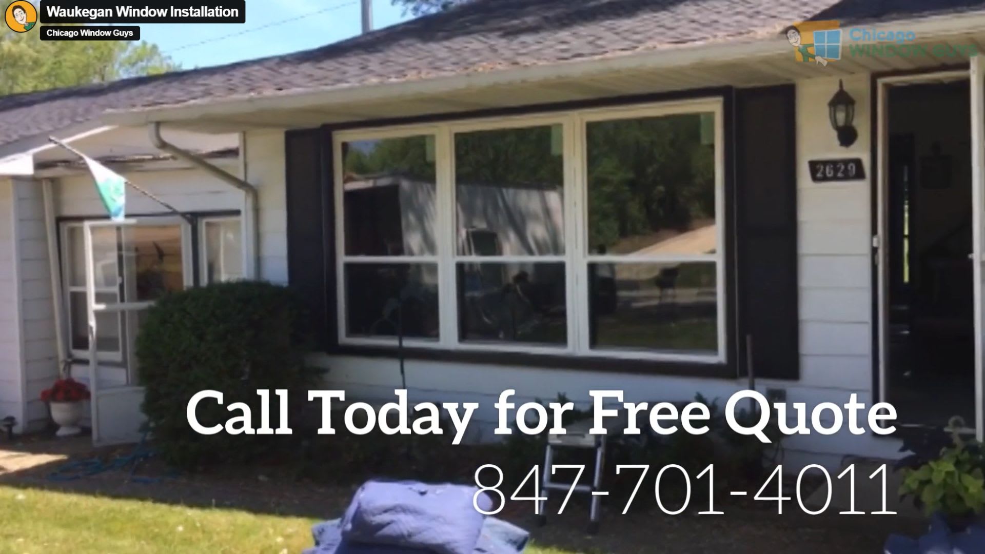 A white house with large front windows and a phone number displayed for window installation quotes: 847-701-4011. Blue blankets are spread on the lawn.