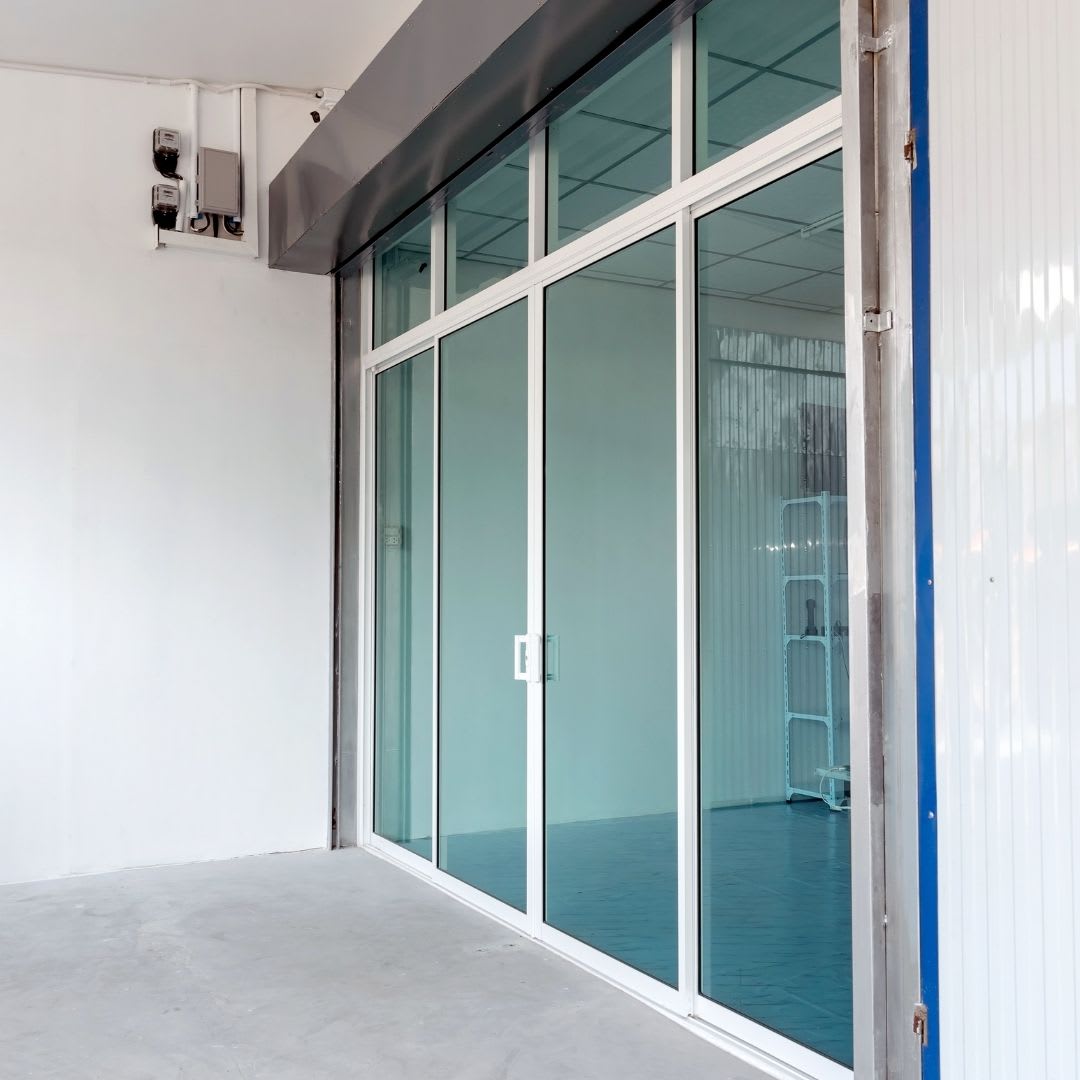 A sliding glass door with a white frame separates an empty indoor space from the outdoor concrete area, ideal for those considering sliding door replacement or seeking styles like sliding doors Chicago.