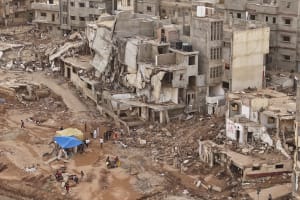 Retter und Angehörige sitzen vor eingestürzten Gebäuden nach den jüngsten Überschwemmungen durch den Mittelmeersturm Daniel in Derna, Libyen, Montag, 18. September 2023.