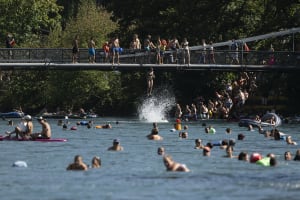 Eine Frau springt von der Schonausteg-Brücke in die Aare bei sonnigem und warmem Wetter in Bern, Schweiz, Sonntag, 20. August 2023.
