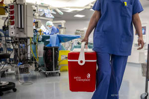 Eine Swiss transplant Kühlbox, die dazu dient, Organe zur Transplantation zu transportieren, wird am Dienstag, den 5. April 2022, in Genf beim Verlassen eines Operationssaals des Universitätskrankenhauses Genf (HUG) fotografiert.