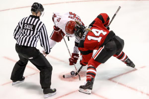 Female ice hockey players engage during faceoff.