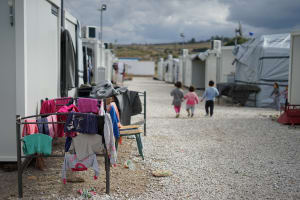 Several small children walk together amongst the temporary shelters in the Moria Refugee Camp