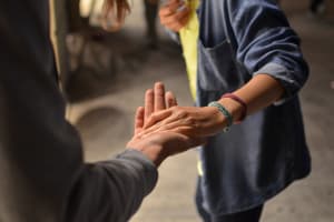 Das Bild zeigt wie eine Person einer anderen die Hand reicht.