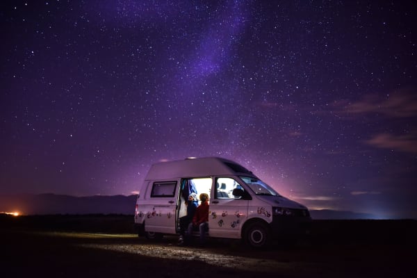 Martina und Dylan, die ganztags in ihrem Wohnmobil leben, sitzen in ihrem Wohnmobil unter dem nächtlichen Sternenhimmel der Mongolei.