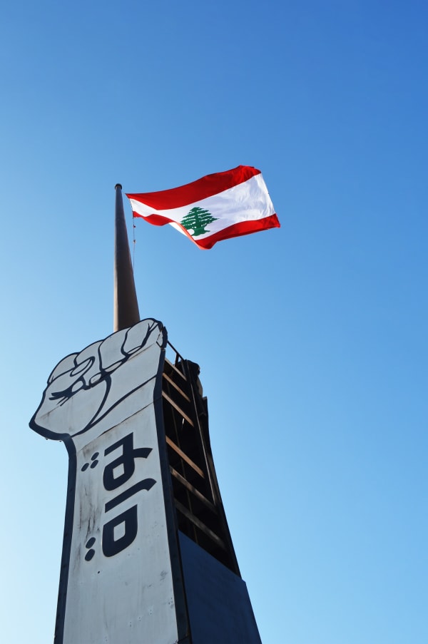 A flagpole adopts the symbol of the Lebanon demonstration movement, a hand with a fist and the Arabic word for revolution