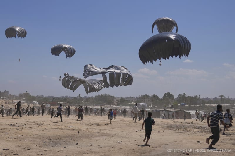 Palästinenserinnen und Palästinenser beeilen sich, humanitäre Hilfsgüter einzusammeln, die mit Fallschirmen in Zawaida im zentralen Gazastreifen abgeworfen wurden, Montag, 4. August 2025.