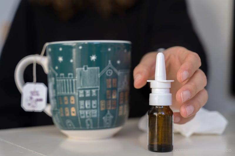 Eine Frau greift nach Nasenspray.