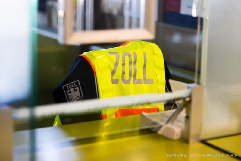 Eine gelbe Warnweste mit der Aufschrift 'Zoll' hängt über einem Stuhl im Gebäude am Grenzübergang in Weil am Rhein.