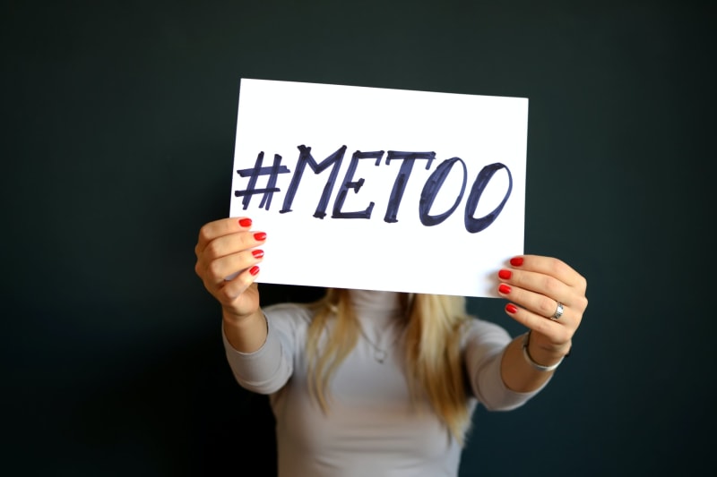 A women holds up a sign with the hashtag '#metoo' written on it