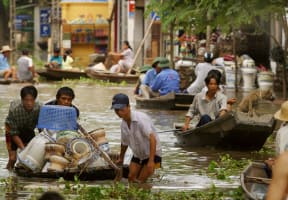 Vietnamesische Handwerker transportieren am Dienstag, dem 20. August 2002, Töpferwaren durch eine überflutete Straße im Dorf Bat Trang, das für seine Töpferkunst bekannt ist und am Stadtrand von Hanoi liegt.