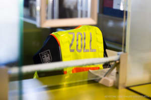 Eine gelbe Warnweste mit der Aufschrift 'Zoll' hängt über einem Stuhl im Gebäude am Grenzübergang in Weil am Rhein.