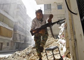 A Free Syrian Army fighter takes cover during clashes with Syrian Army in the Salaheddine neighbourhood of central Aleppo