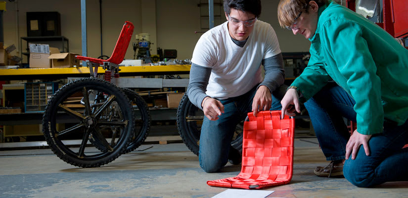 two engineering students work on a seat for a moon buggy