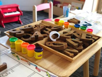 Early Childhood Education: Child's table filled with various wooden blocks with letters and Play-doh