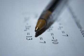 Mathematics: ball point pen laying on paper with a math equation