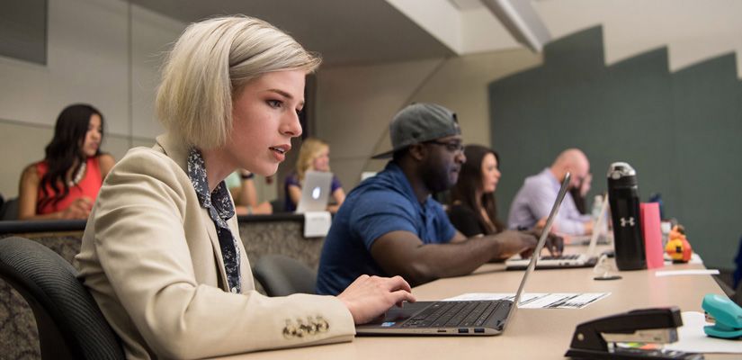 students in a classroom focusing on their screens