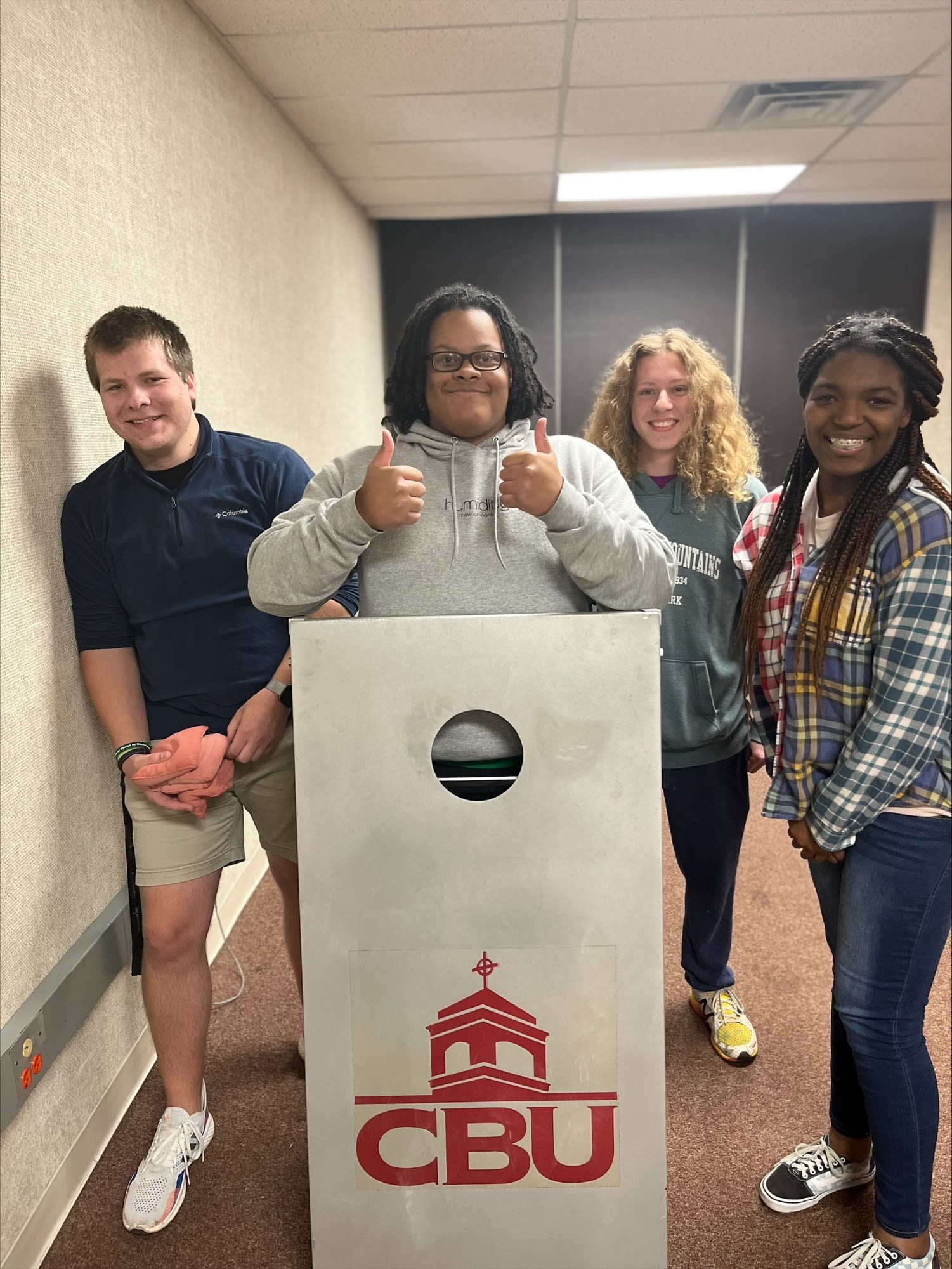 4 Honors Students holding one end of a corn hole yard game.