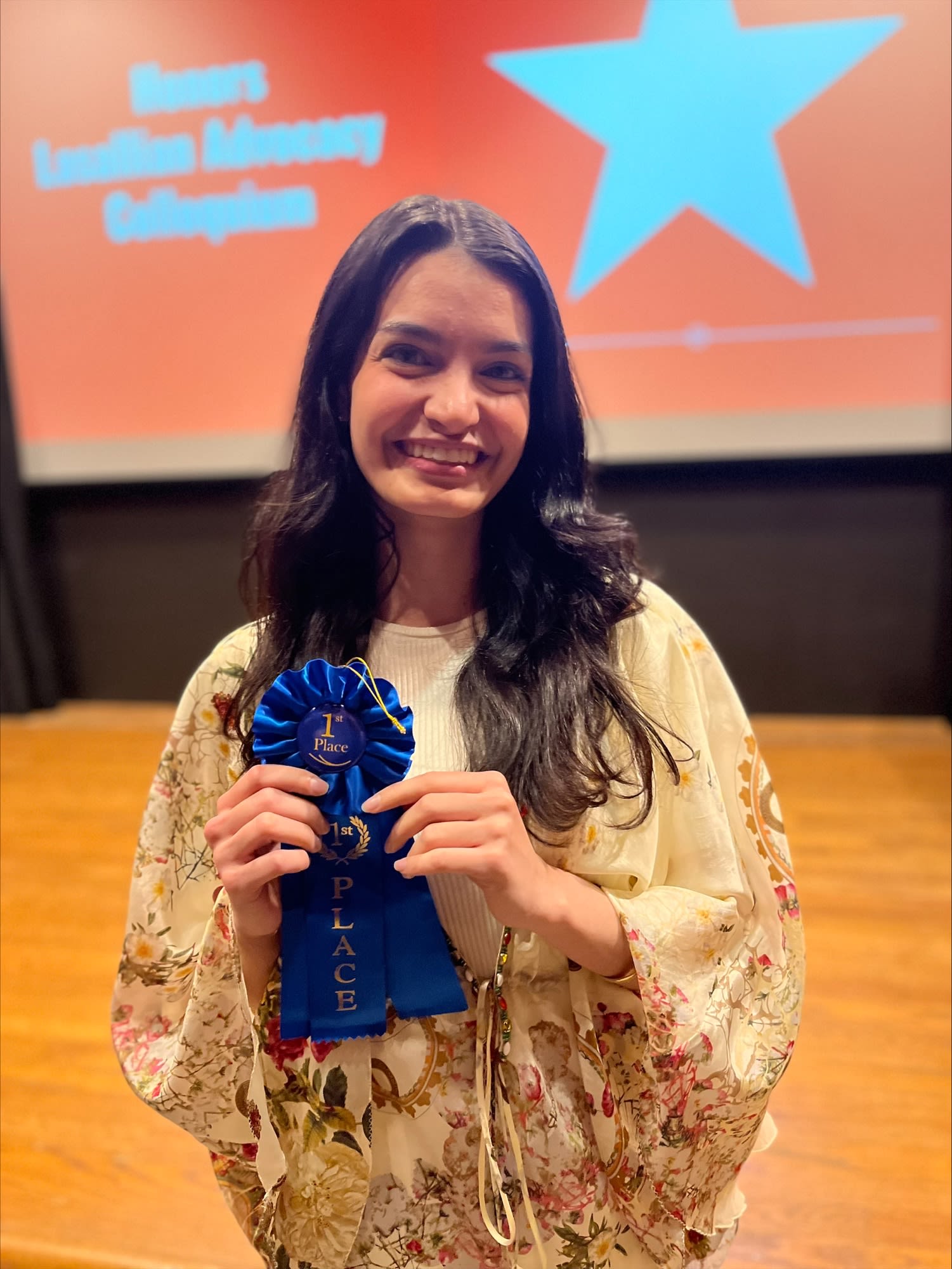 One honors student holding a blue ribbon.