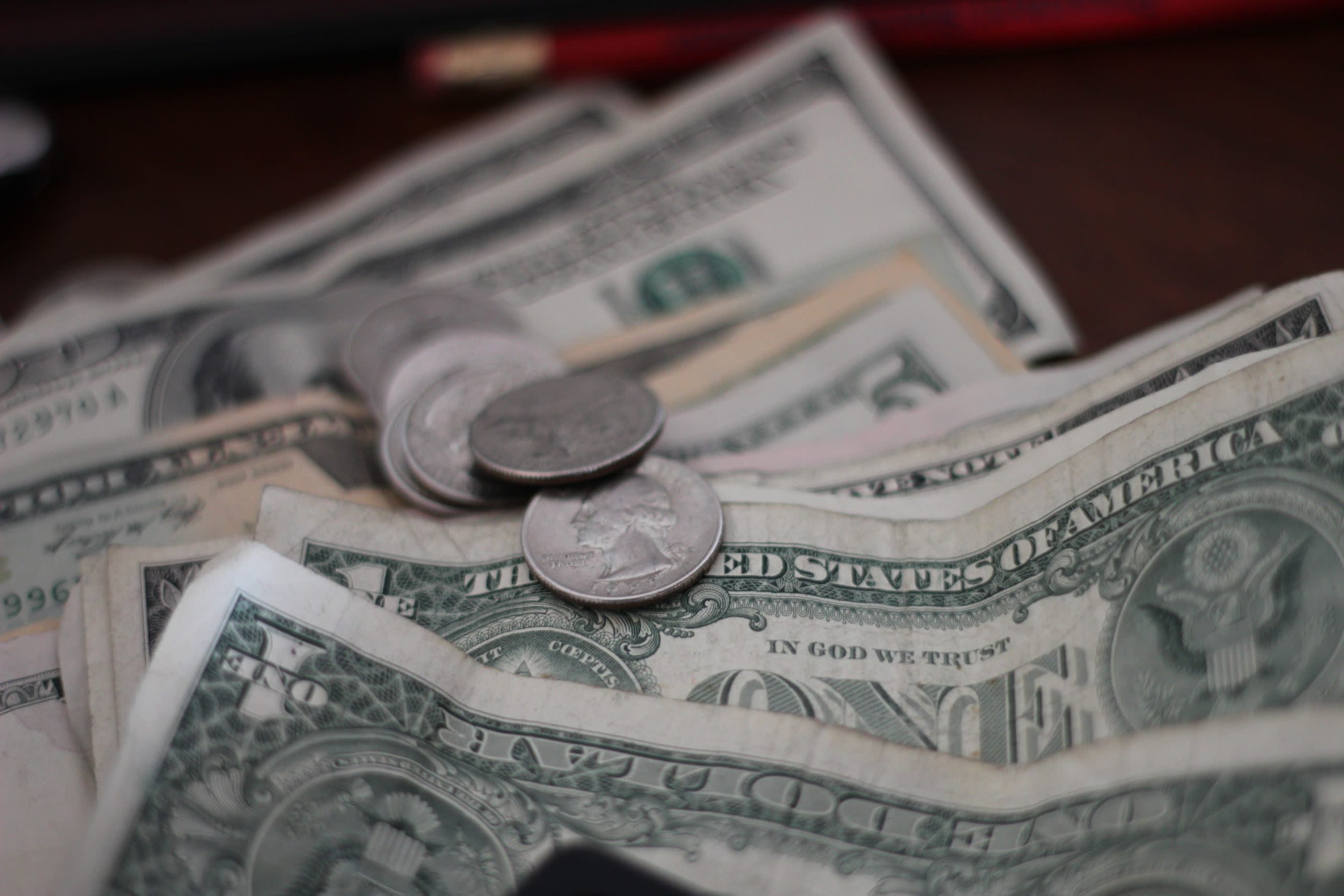 a few quarters and dollars bills of various value on a table