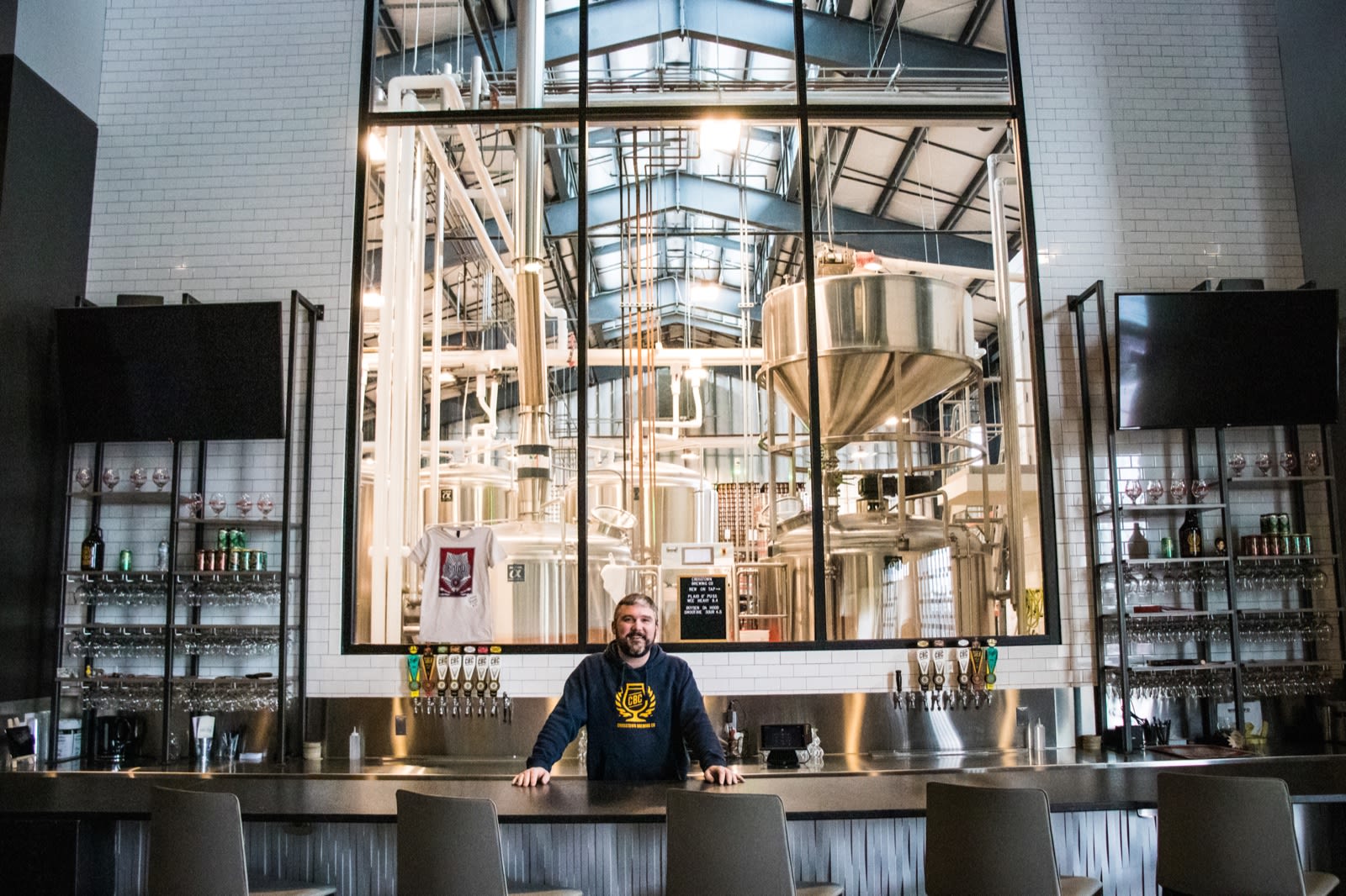 CBU Alumni standing behind the counter at the brewery he owns.