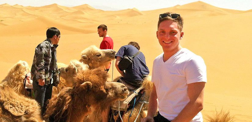 Students riding camels in the desert