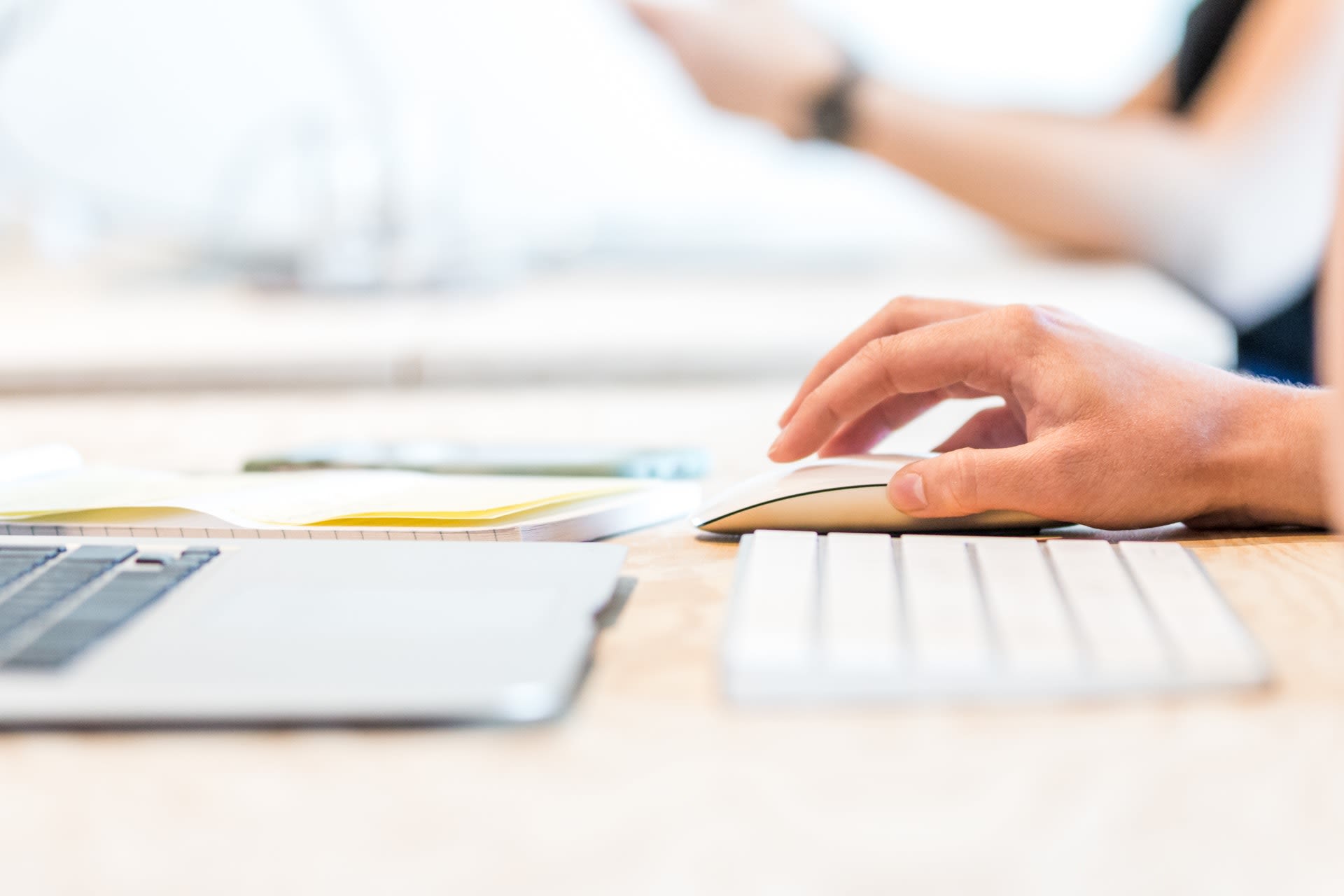 Hand using a wireless mouse while working at a laptop computer