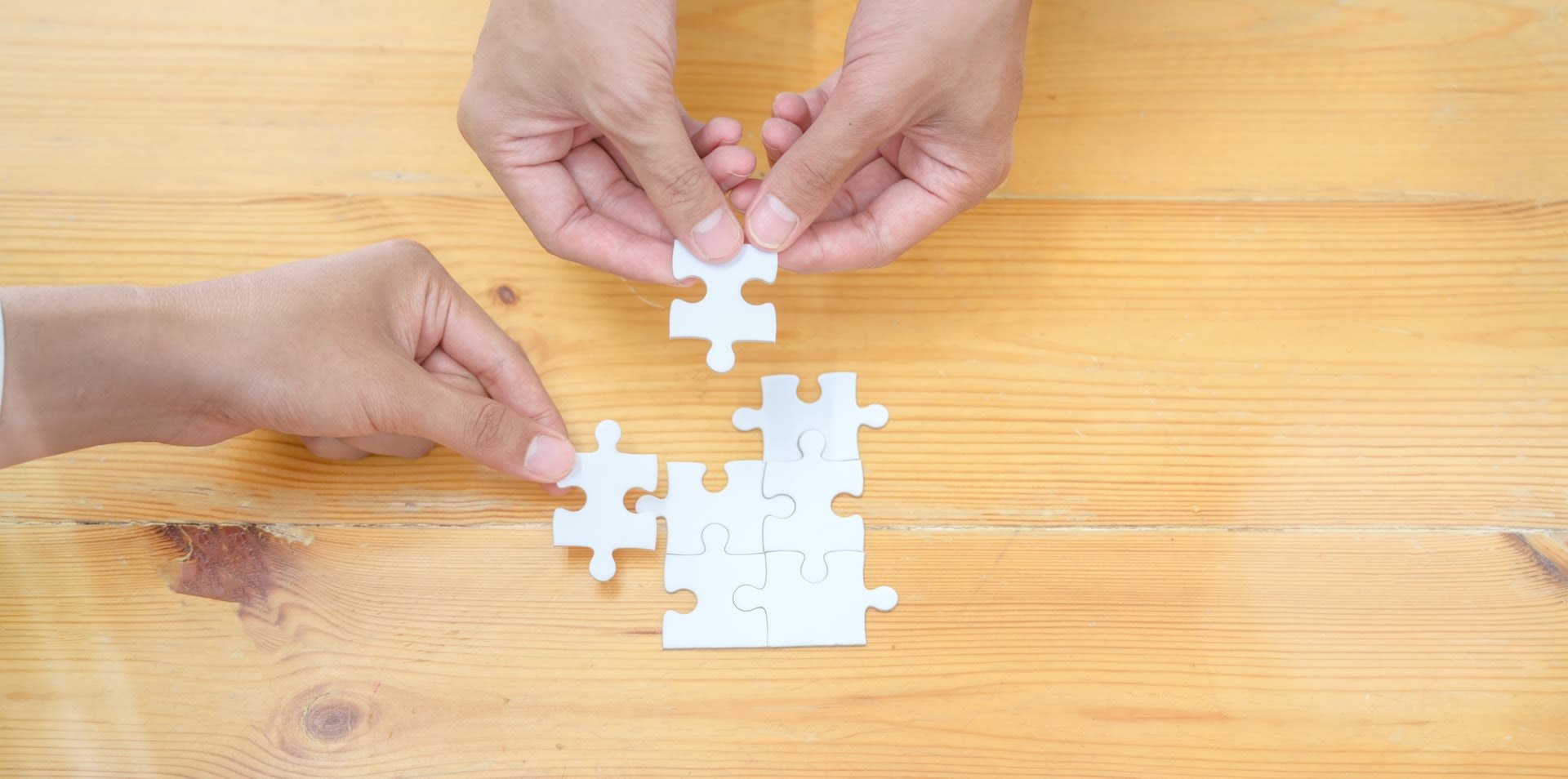 Person holding white jigsaw puzzle piece
